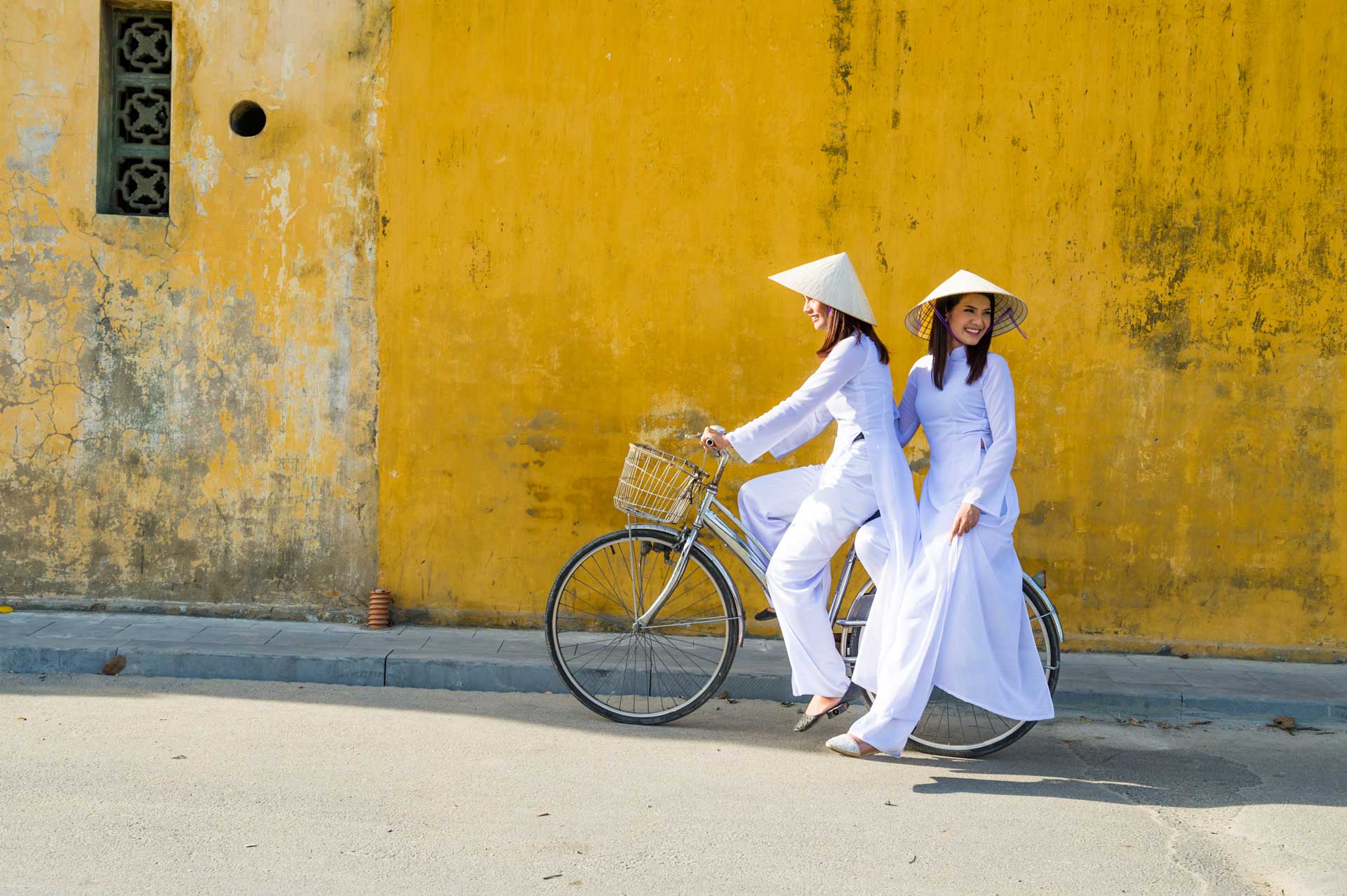 Vietnam girls with a vietnamese traditional costume wearing Ao dai ride a bicycle at Hua. Many vietnam woman in hue city still wearing traditional dress.Hue is old town and many history building